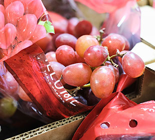 Fresh ripe grapes spill out of their packaging within a fruit box ready for pickup or delivery from Martinous Produce.